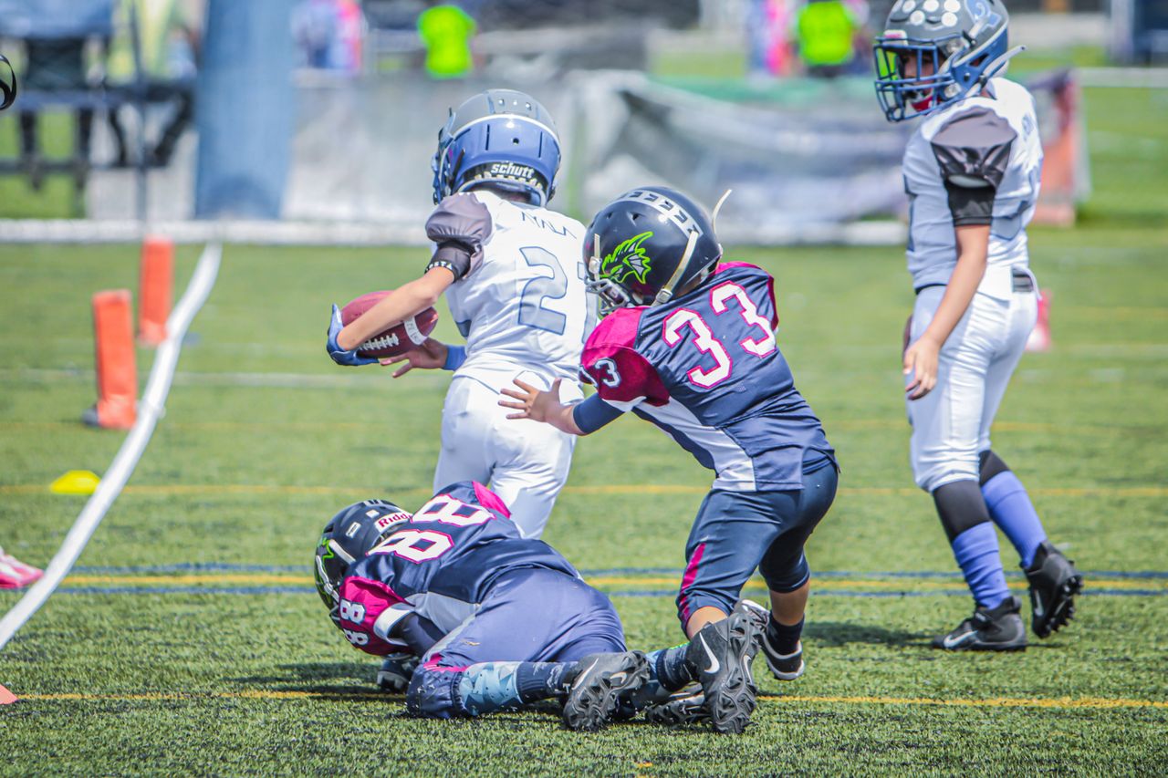 two-youth-pop-warner-football-players-kids-tackling-a-child-running-with-the-ball